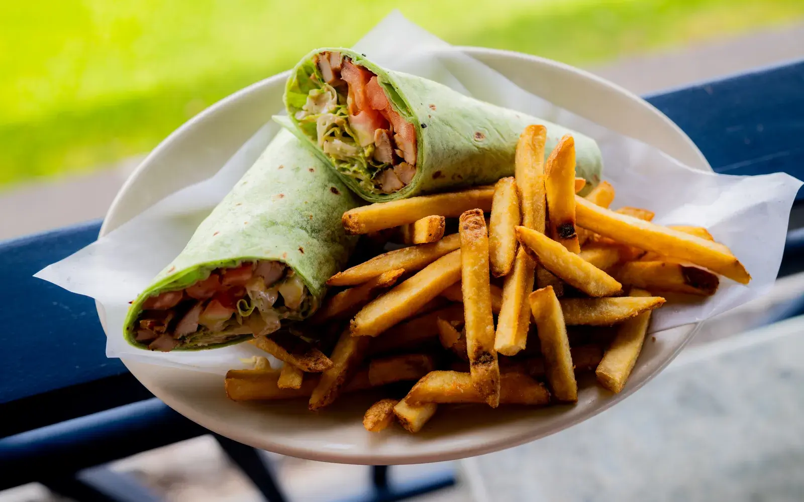 Grilled chicken wrap with golden fries on the Harbor House lanai