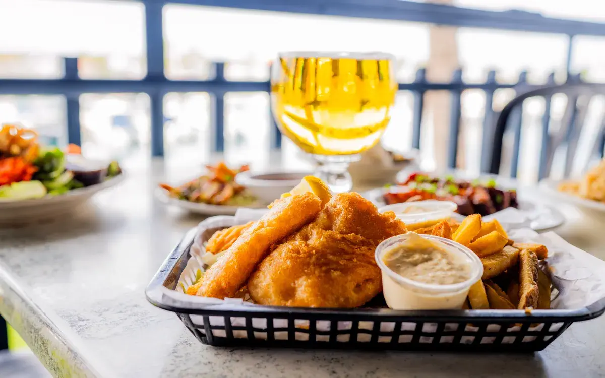Fish and chips basket with an ice-cold schooner at the harbor rail