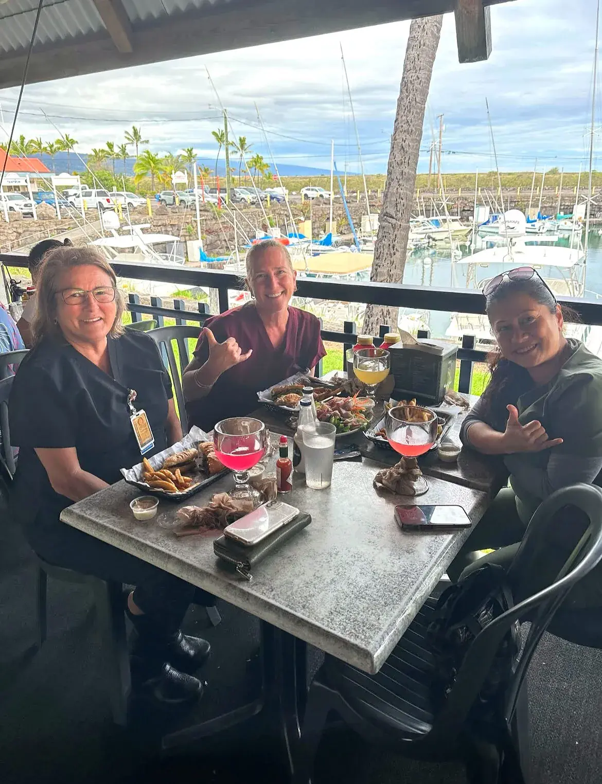 Friends gathered for drinks on the harbor-side deck at Harbor House Kona