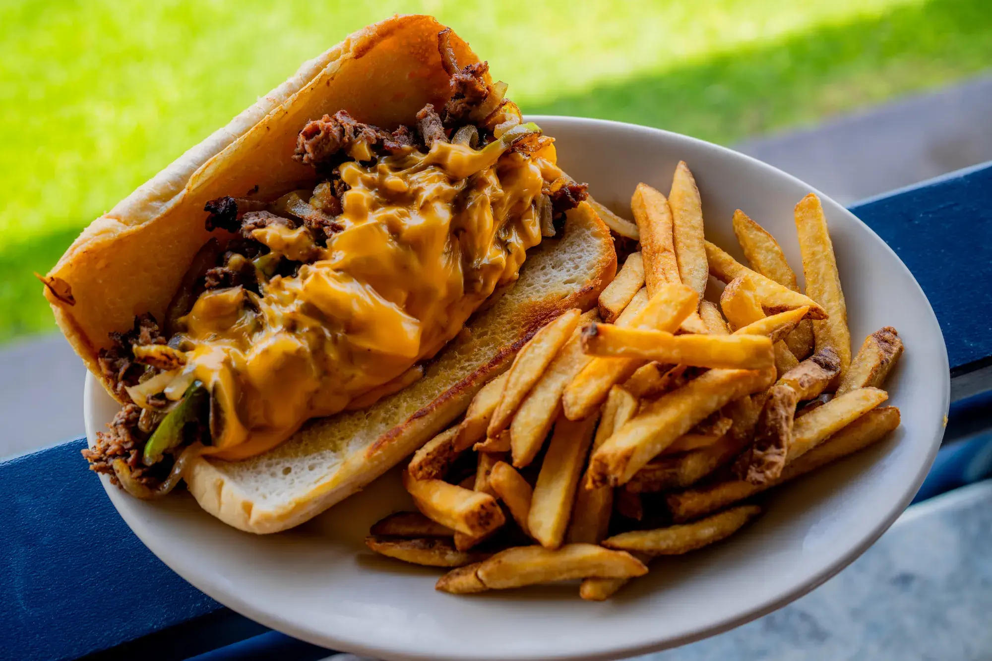 Philly Cheese Steak at Harbor House Kona, Thin-sliced beef, cheddar cheese & grilled onions, bell peppers on French bread | Add lettuce & tomato +$3.
