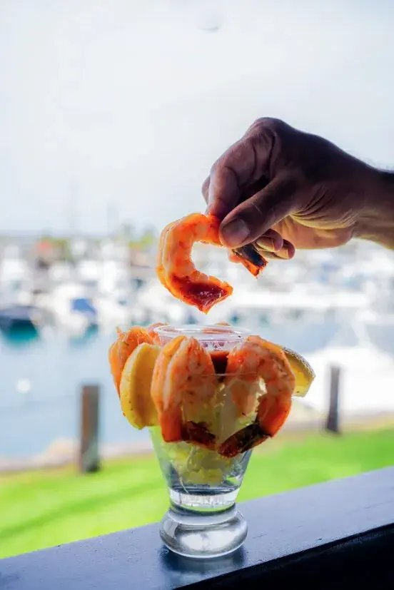 Chilled shrimp cocktail held up against the Honokohau marina at Harbor House Kona