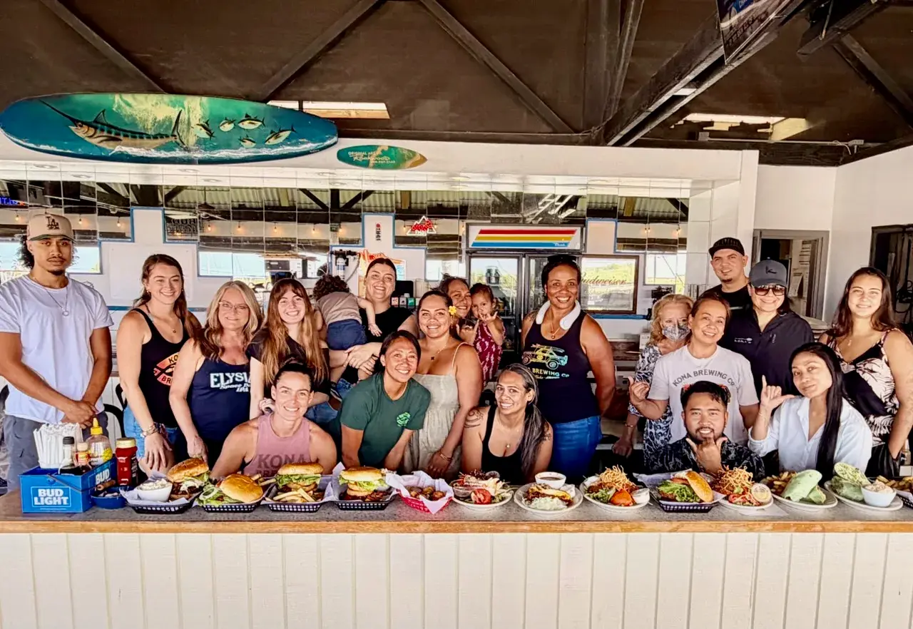 The Harbor House crew lined up behind the bar with plates of burgers, wraps and pupus