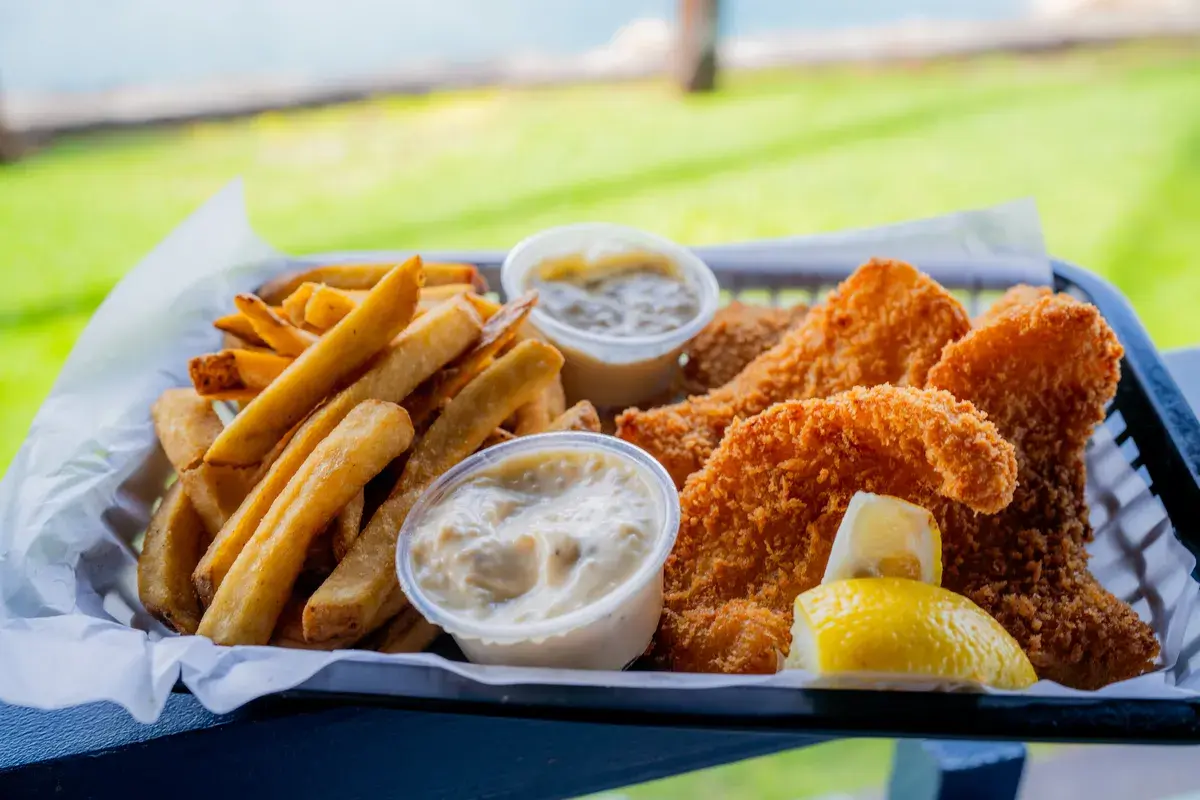 Beer-battered fish and chips basket at Harbor House Kona with the harbor lawn behind it