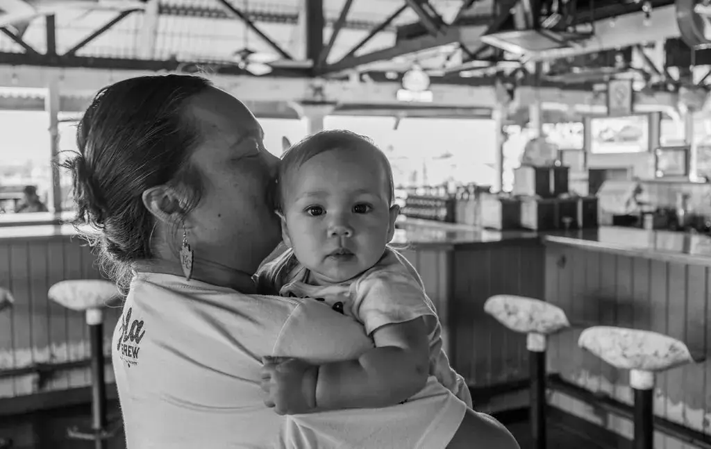 A mother holding her baby at the Harbor House Kona counter