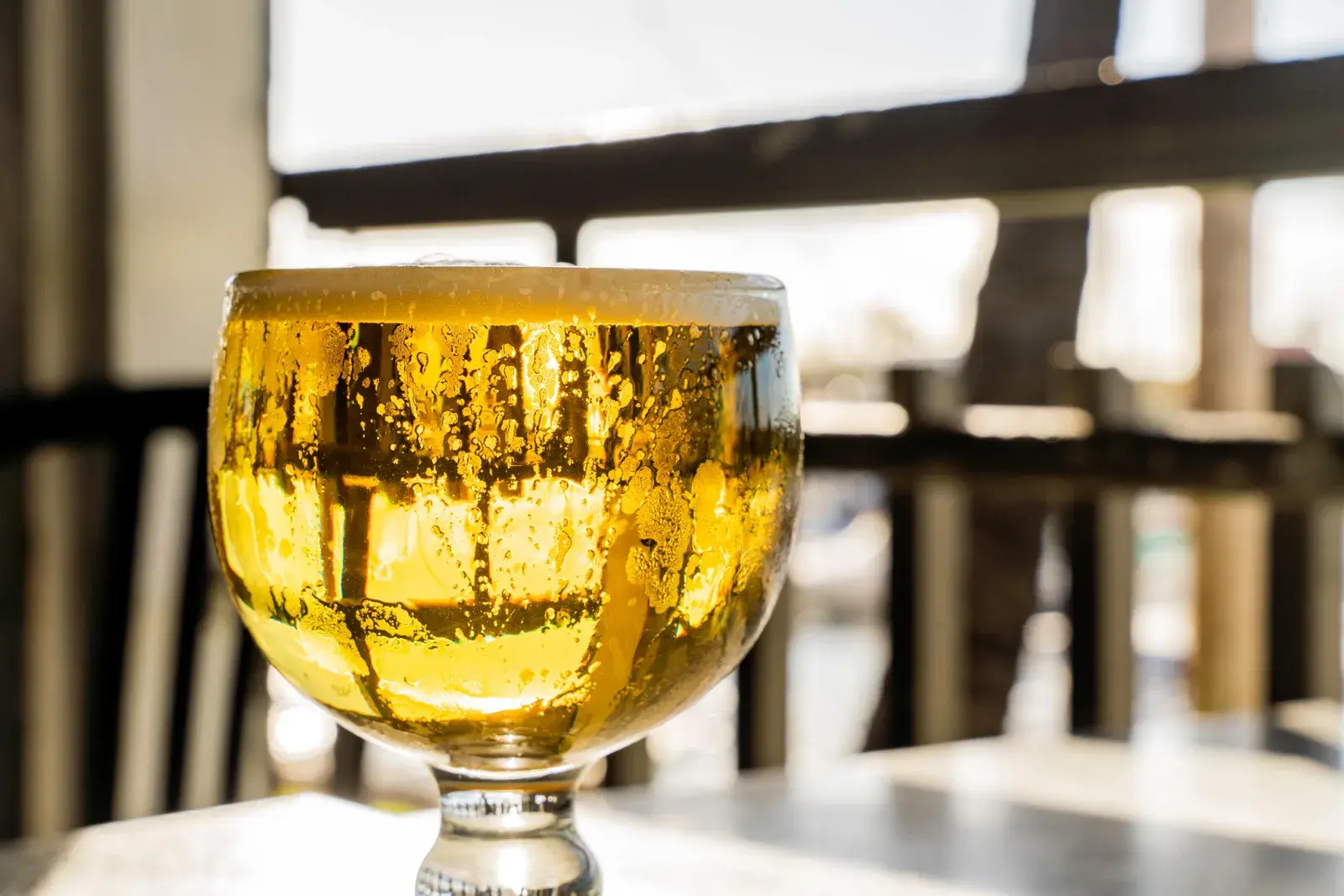 Ice-cold golden schooner of draft beer on a table in the open-air dining room
